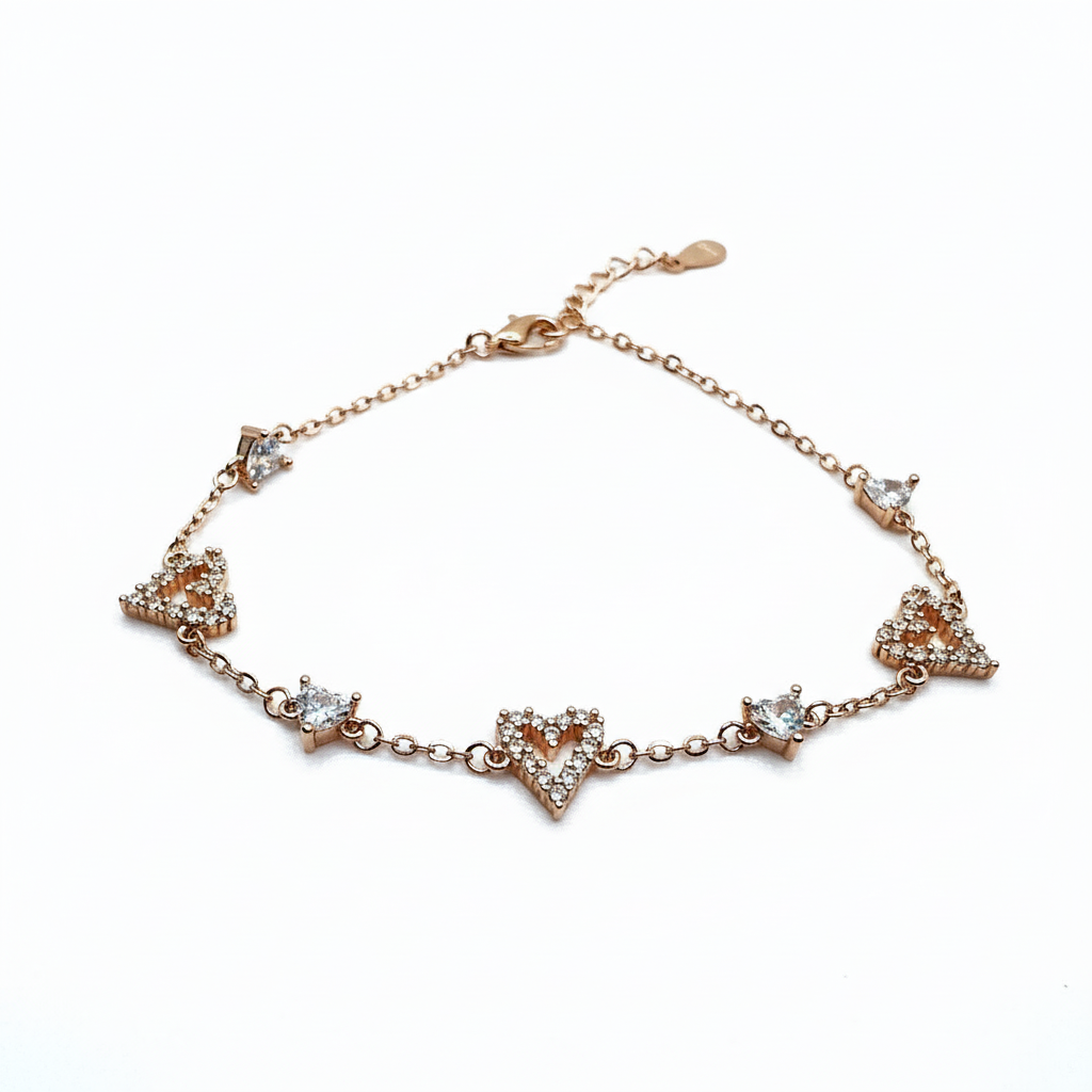 Rose gold bracelet with heart and triangle designs on a white background