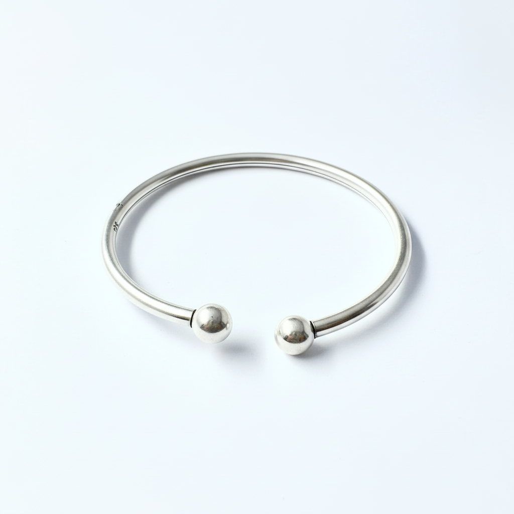 Silver bracelet with two spherical charms on a light gray background