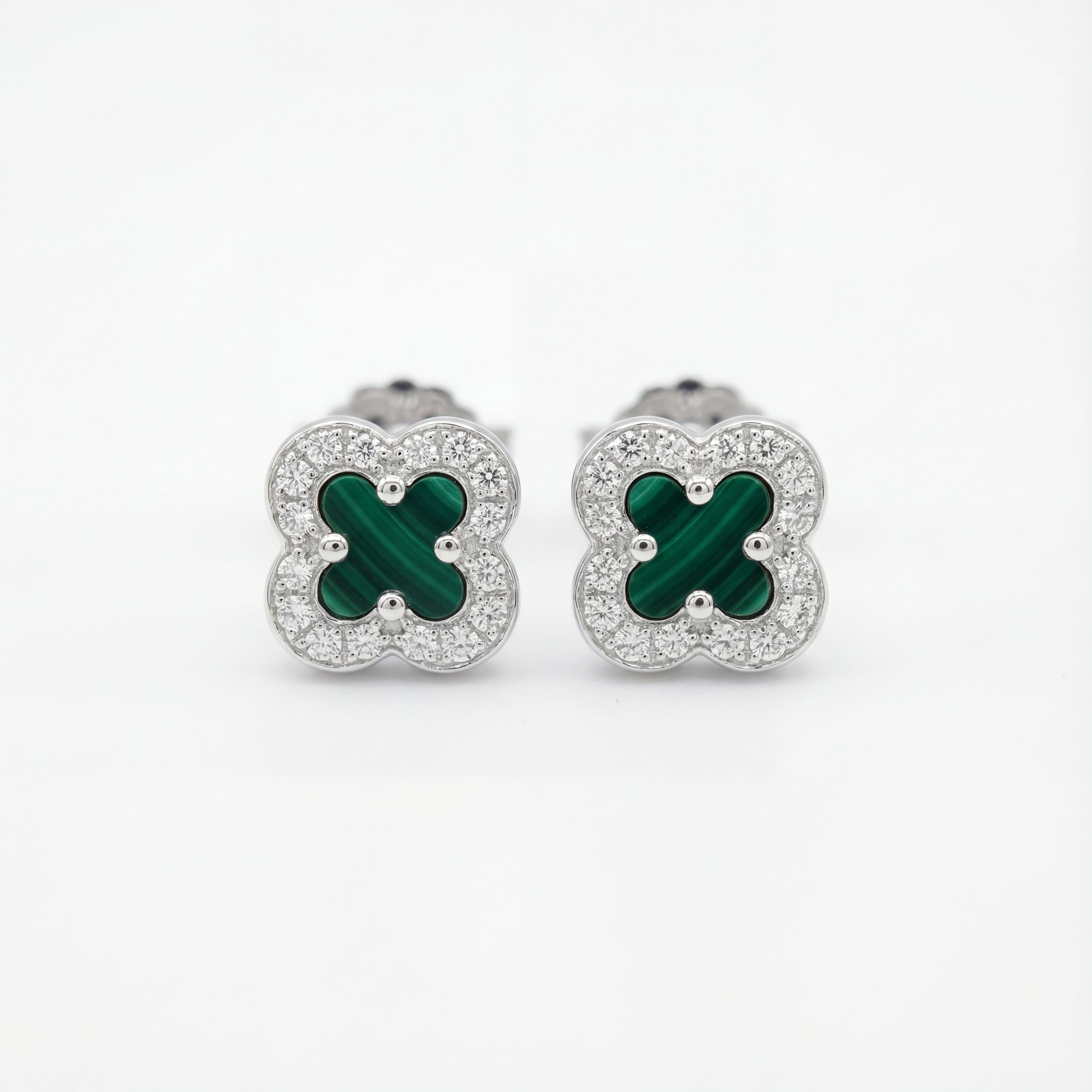 Pair of clover-shaped earrings with green centers and silver borders on a white background
