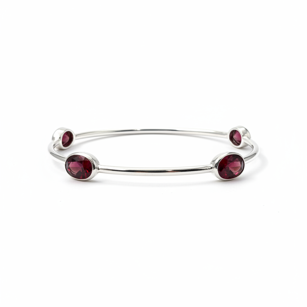 Silver bangle with red gemstones on a white background