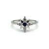 Silver ring with a blue gemstone and smaller diamonds on a white background