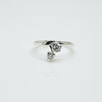 Silver ring with two heart-shaped gemstones on a white background