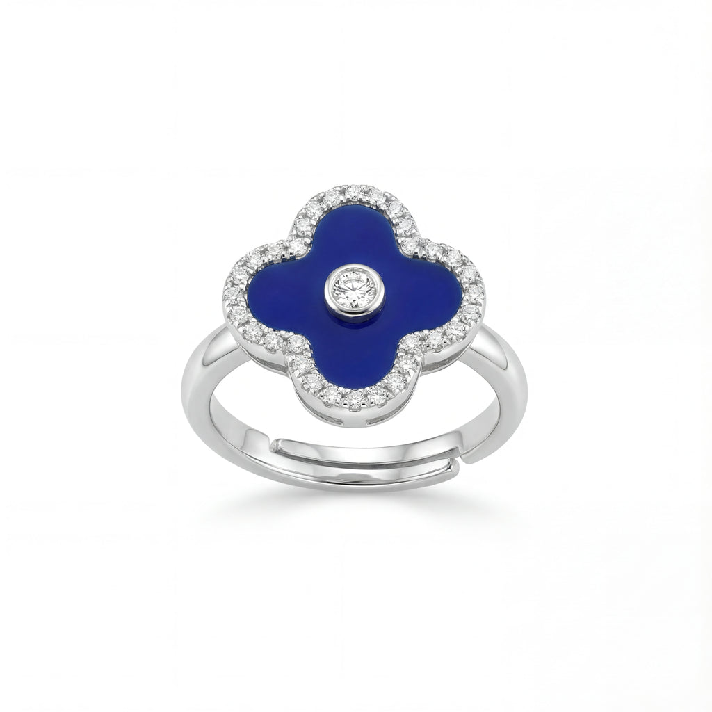 Silver ring with a blue clover-shaped stone and clear stones on a white background