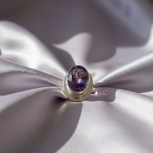 Gold ring with a purple gemstone on a soft, light-colored fabric background